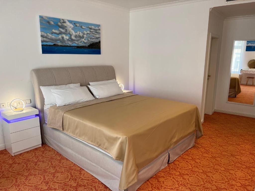 Modernes Doppelzimmer „Festspielhaus“ mit großem Kingsize-Bett, stilvollen Nachttischen und heller Einrichtung auf elegant gemustertem Teppichboden.